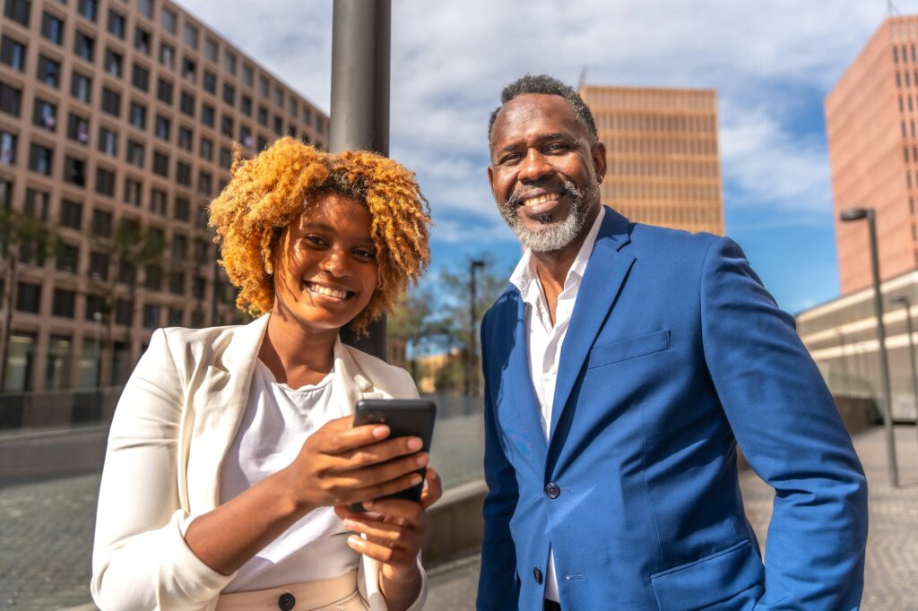 Smiling african business people using phone outdoors